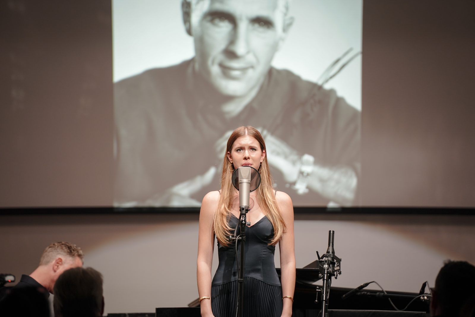 Lilah Anders sings From Up Here beneath a portrait of her grandfather, Apollo 8 astronaut Bill Anders